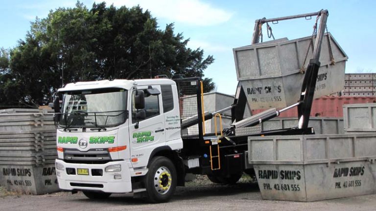 white Rapid Skips delivery truck with green logo on the side picking up skip bin hire in Shellharbour on NSW South Coast